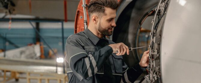 Smiling,Man,Airline,Maintenance,Technician,Using,Screwdriver,While,Repairing,Airplane